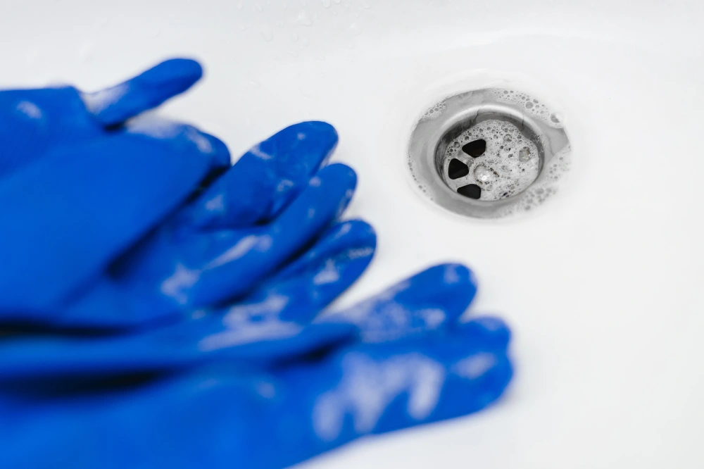Blue gloves in the sink after washing dishes. Bathroom cleaning concept.